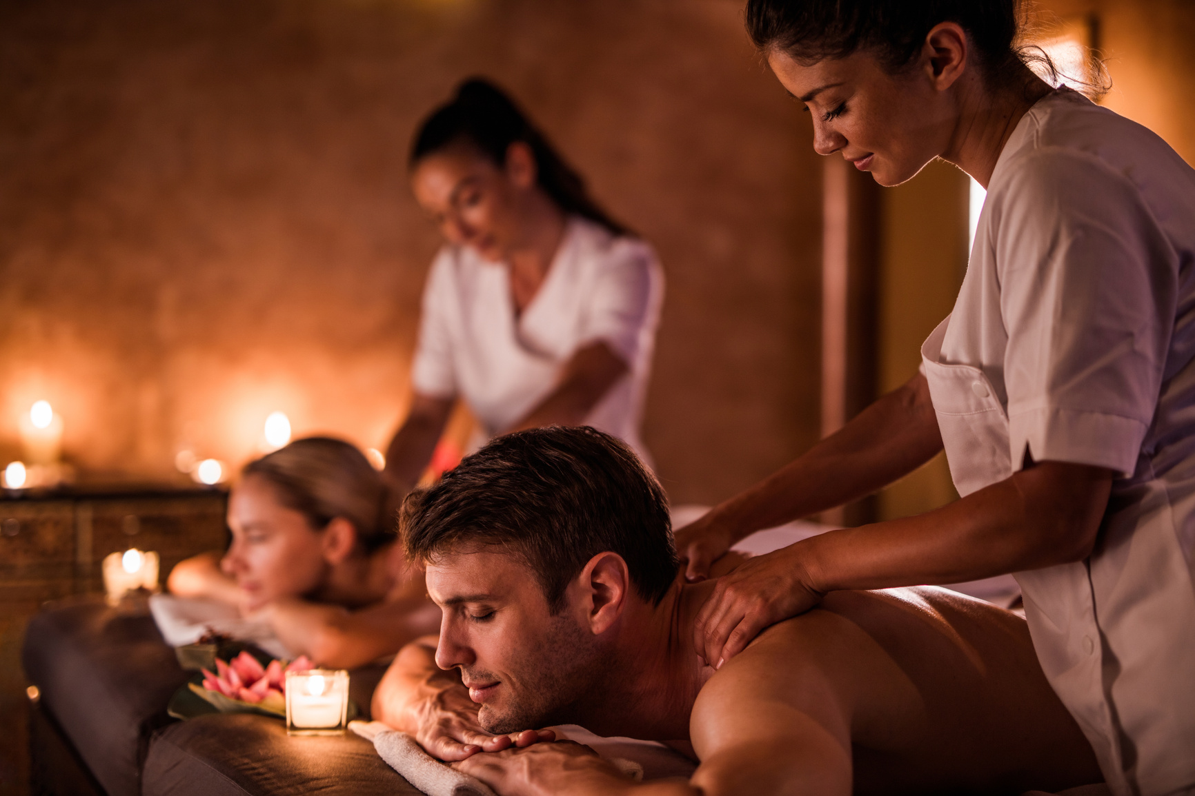 Female massage therapists massaging young couple at the spa.
